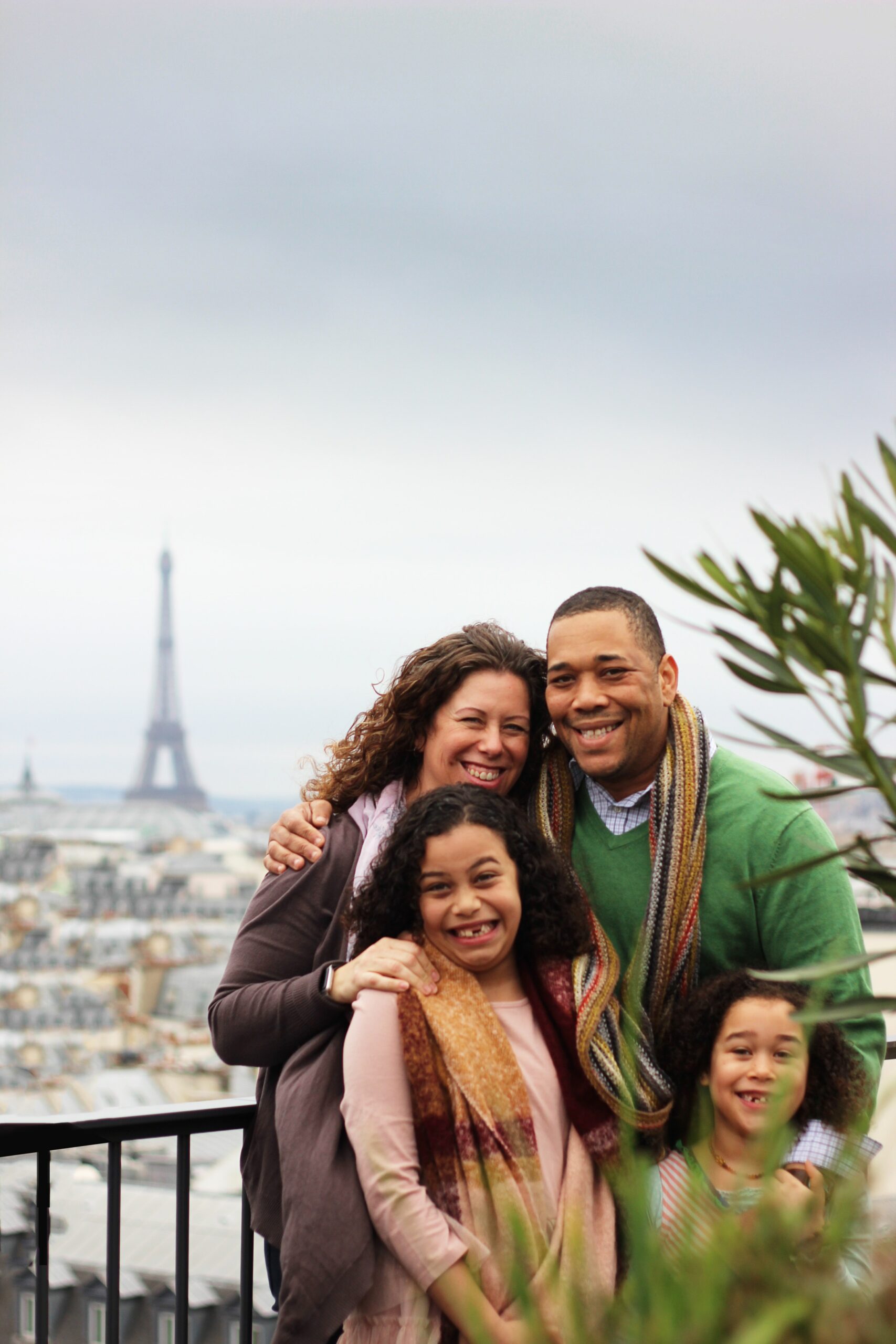 family of four posing in front of eiffel tower